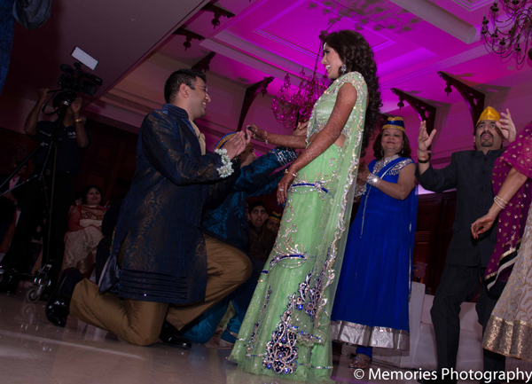 The Indian groom takes a knee for his bride at the traditional sangeet.