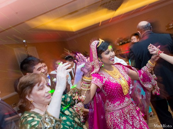 This Indian wedding features a bride in a bright pink lengha, beautiful floral and decor, and a traditional Pakistani ceremony.