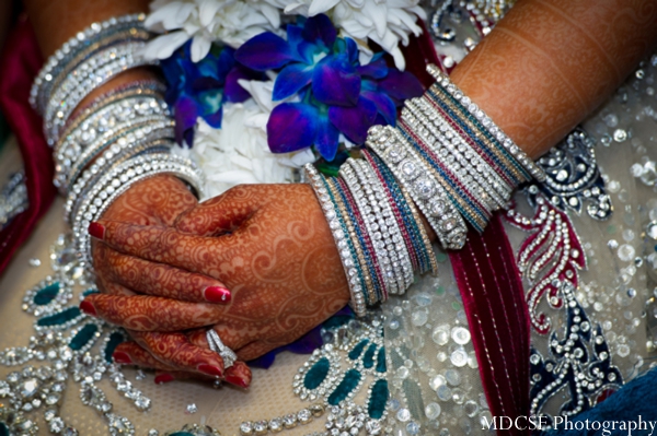 Indian bridal jewery shown on arms decorated with bridal henna.