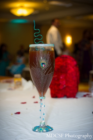 Peacock theme indian wedding party shown on champagne glass.