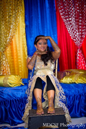 Indian bride shows off her bridal mehndi on her arms and feet.
