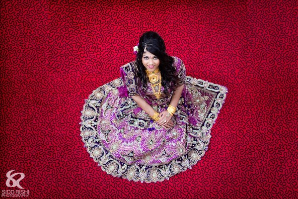 An Indian bride in a purple bridal lengha.