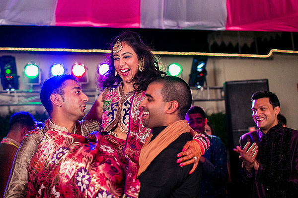 Indian wedding guests hoist up the Indian bride at her sangeet.