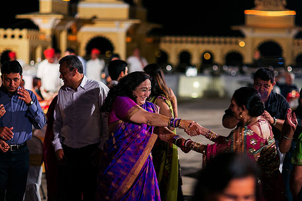 Family members in colorful saris dance at this Indian wedding welcome dinner.