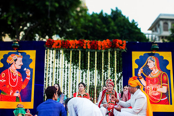This Indian wedding altar is decorated with large paintings and flower garlands.