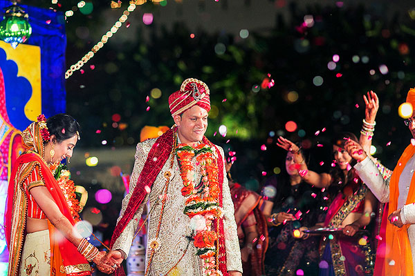 An Indian bride and groom are covered in confetti as they become husband and wife.
