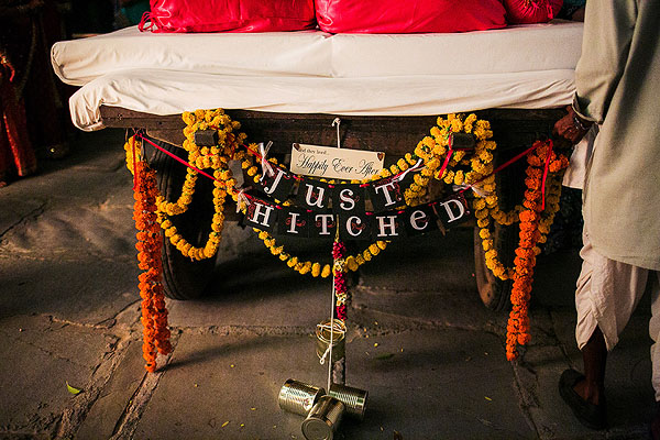A camel cart reads "just hitched" as it waits to take away an Indian bride and groom.
