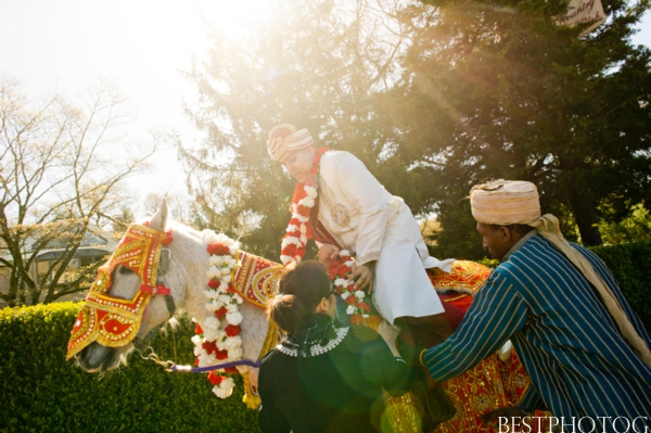 A groom gets on a horse to arrive to his Indian wedding.