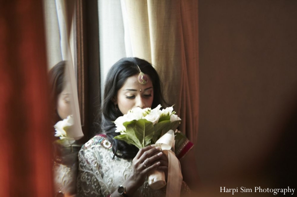 An Indian bride sniffs at her indian bridal bouquet of white and green.