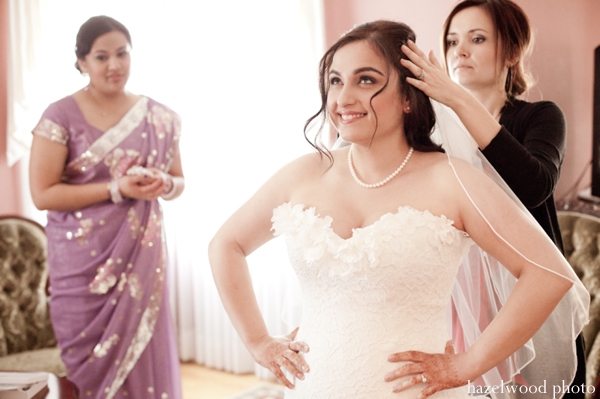 Indian bride slips on a white wedding gown for her fusion Indian wedding.