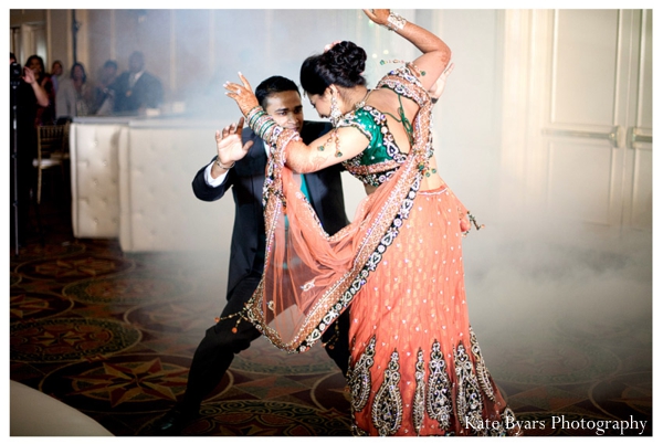Indian bride dances with groom in a bridal lengha at her indian wedding reception.