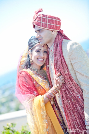 Indian bride wears red and yellow wedding lengha next to her groom.