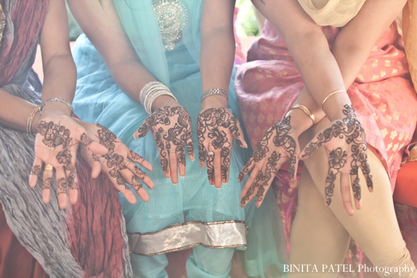 Henna artist draws bridal mehndi for Indian bride and bridesmaids.