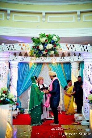 Indian bride and groom under a white mandap.