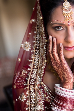 Indian bride in rose wedding lengha and bridal mehndi on hands