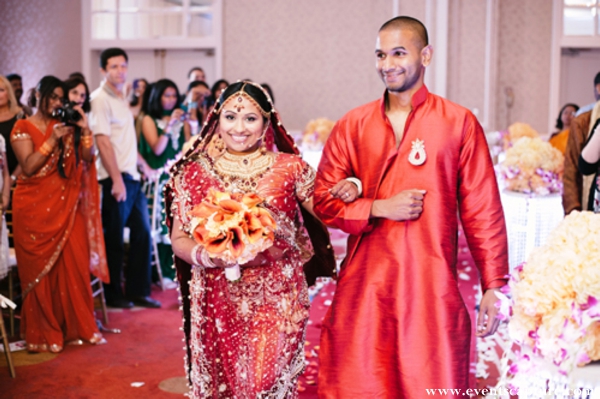 Indian bride in red wedding lengha walks into her indian wedding ceremony