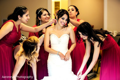 The bridal party helps the bride get ready in her white wedding gown.