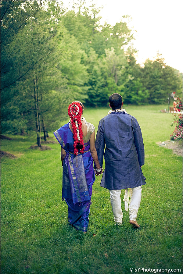 An Indian bride and groom walk off into the sunset.