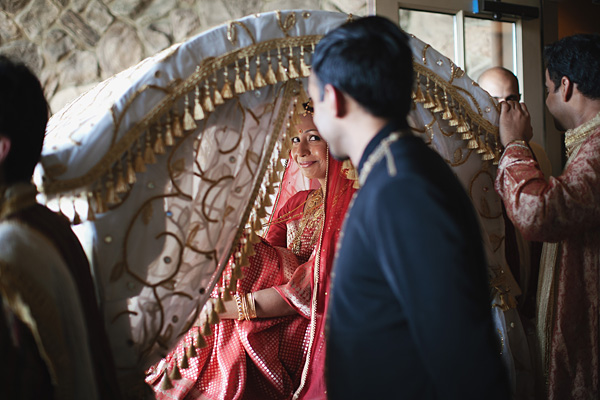 An Indian bride arrives to her outdoor wedding in a palanquin.