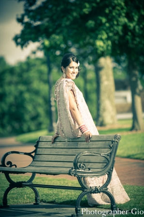 An Indian bride poses in her baby pink bridal lengha.